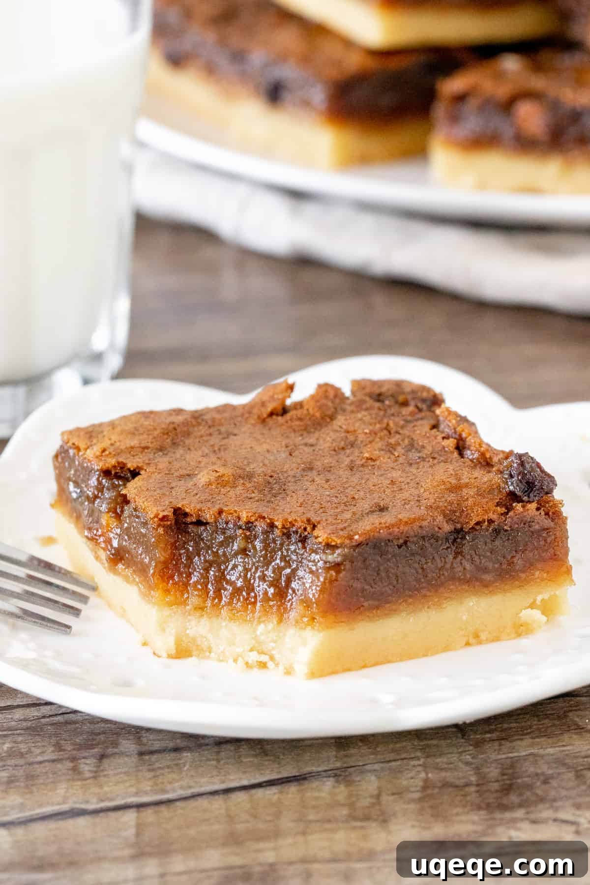 A single, perfectly baked butter tart square with a bite taken out, revealing the thick, golden shortbread crust and the generous, glistening layer of gooey filling inside.
