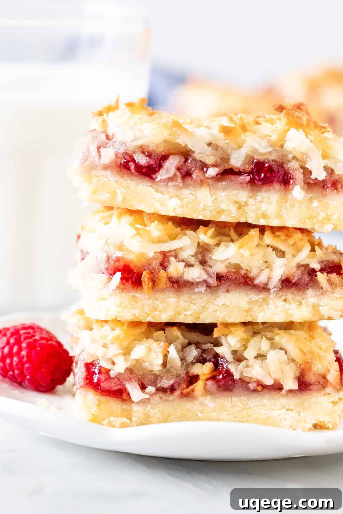 Raspberry Coconut Delights 5 Stack of three perfectly sliced raspberry coconut bars, showing the shortbread, jam, and golden coconut layers from a high angle.