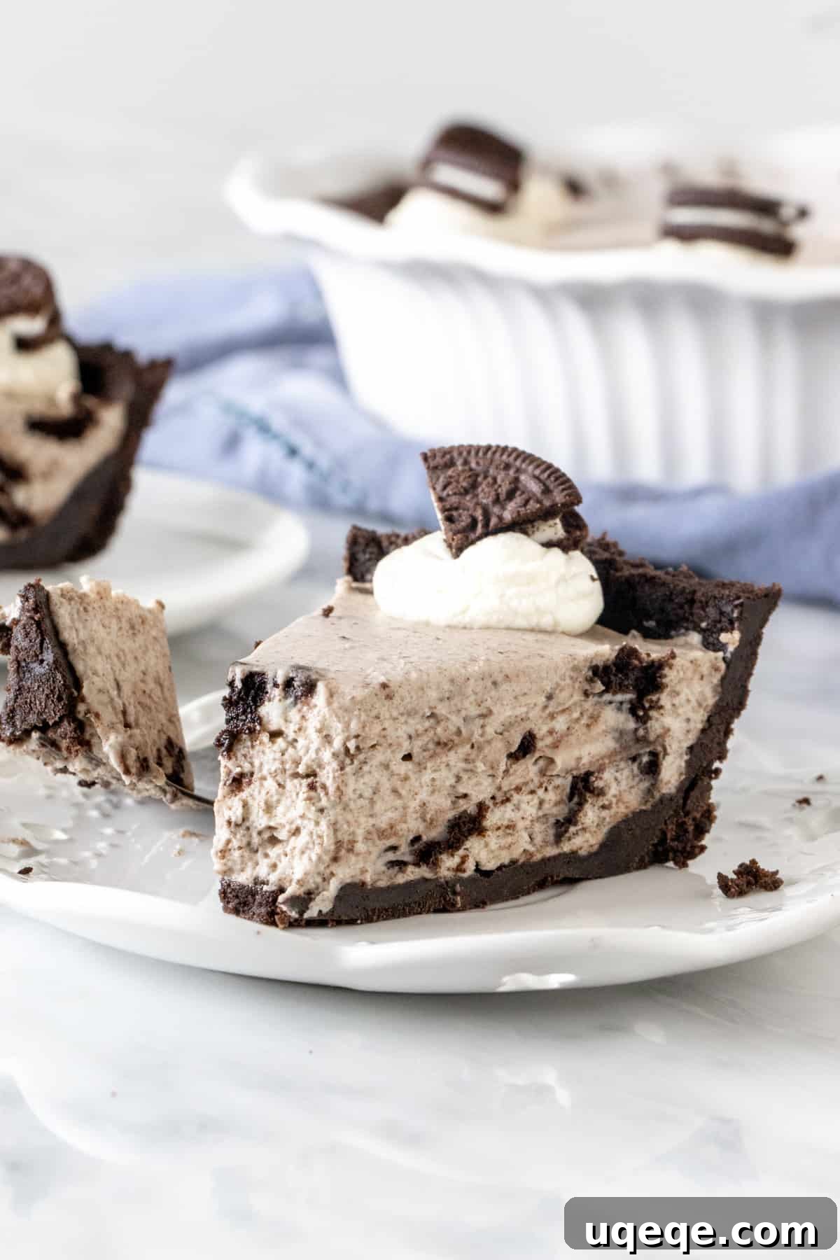 Ultimate Oreo Indulgence 2 Slice of creamy Oreo pie on a white plate, showcasing the thick crust and cookie-filled interior.