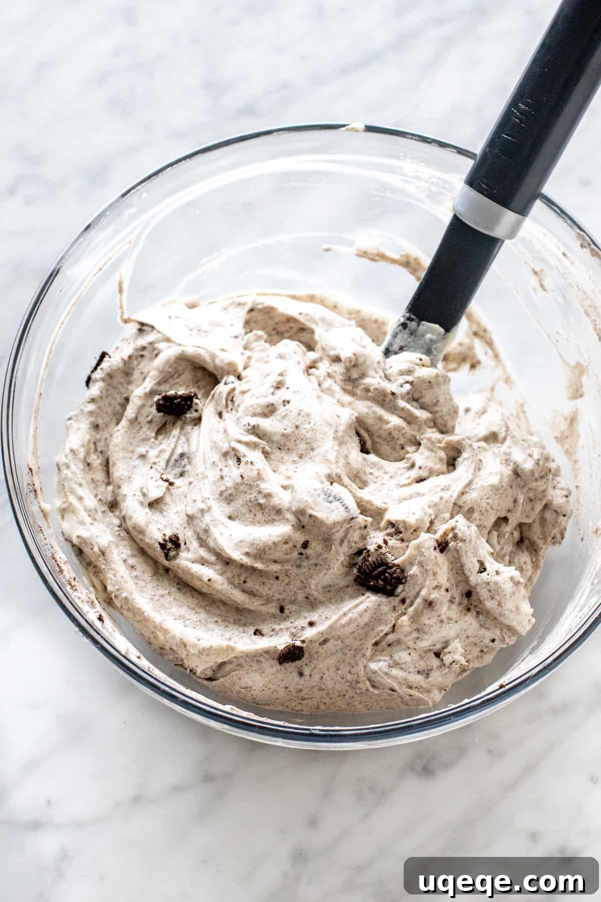 Ultimate Oreo Indulgence 5 A bowl of creamy, white filling mixed with visible crushed Oreo cookies, ready to be spooned into the crust.