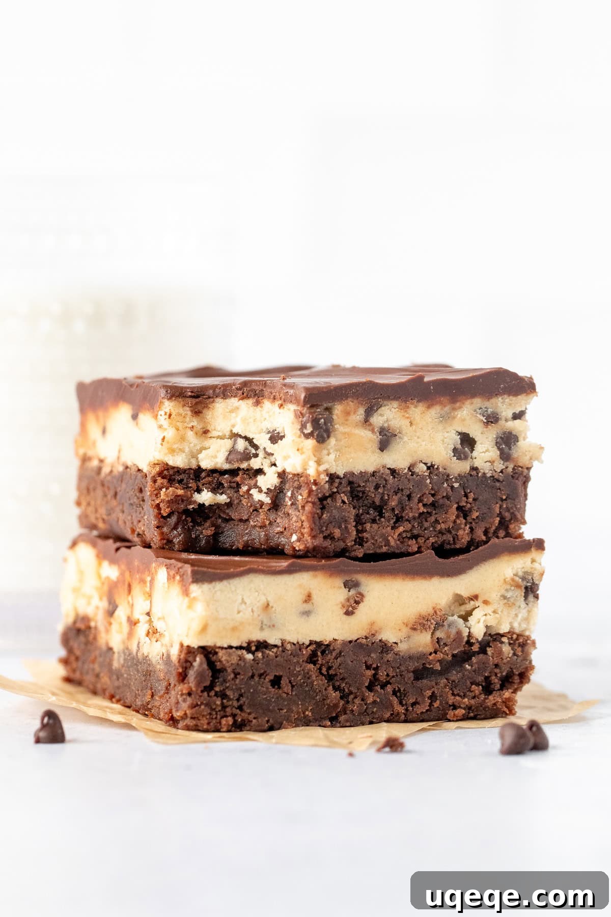 Ultimate Cookie Brownie Bars 11 Two perfectly cut cookie dough brownies, stacked one on top of the other, with a tempting bite taken out of the top brownie, revealing all three delectable layers.