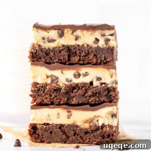 Three cookie dough brownies, stacked one on top of another, showcasing the three delicious layers.