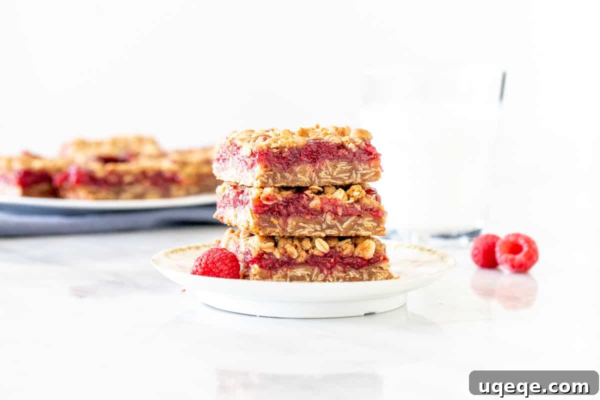 Homemade Raspberry Bars 6 Delicious raspberry bars stacked neatly on a white plate, ready to be enjoyed.