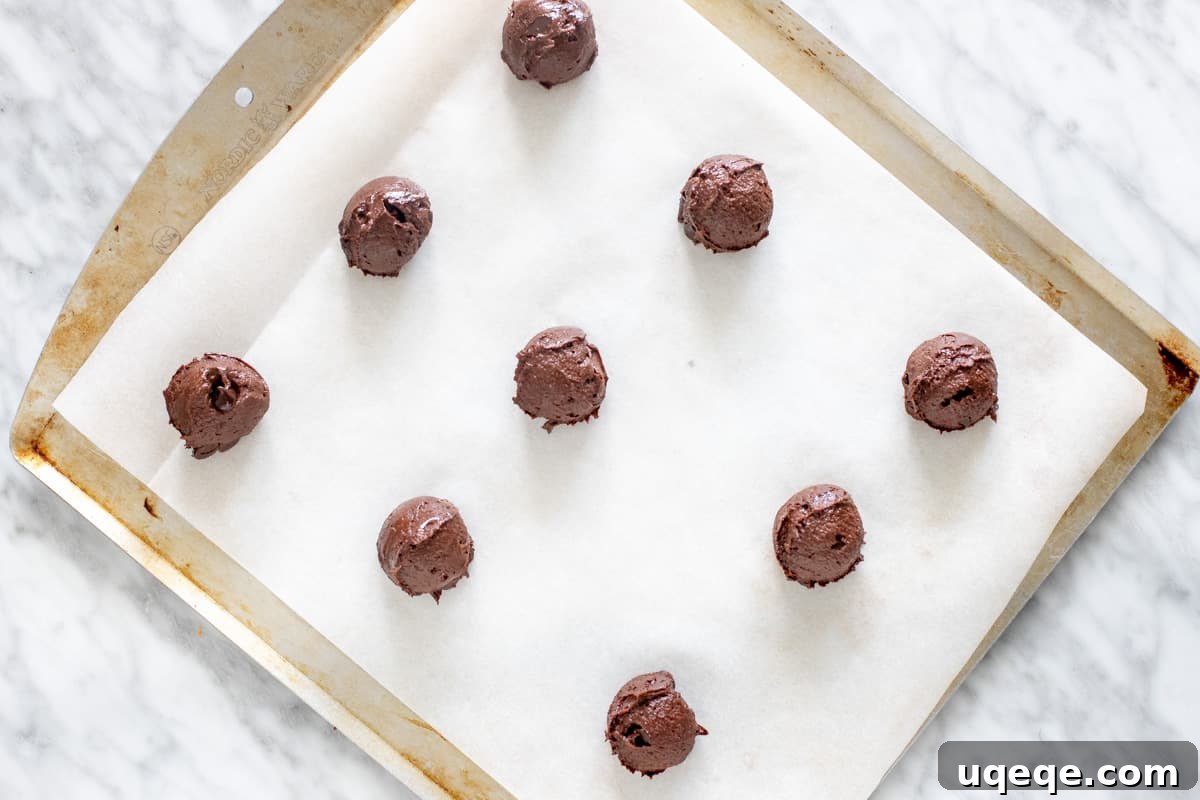 Gourmet Brownie Cookies 6 A baking tray meticulously arranged with evenly spaced, rounded chocolate cookie dough balls, awaiting their transformation in the oven.