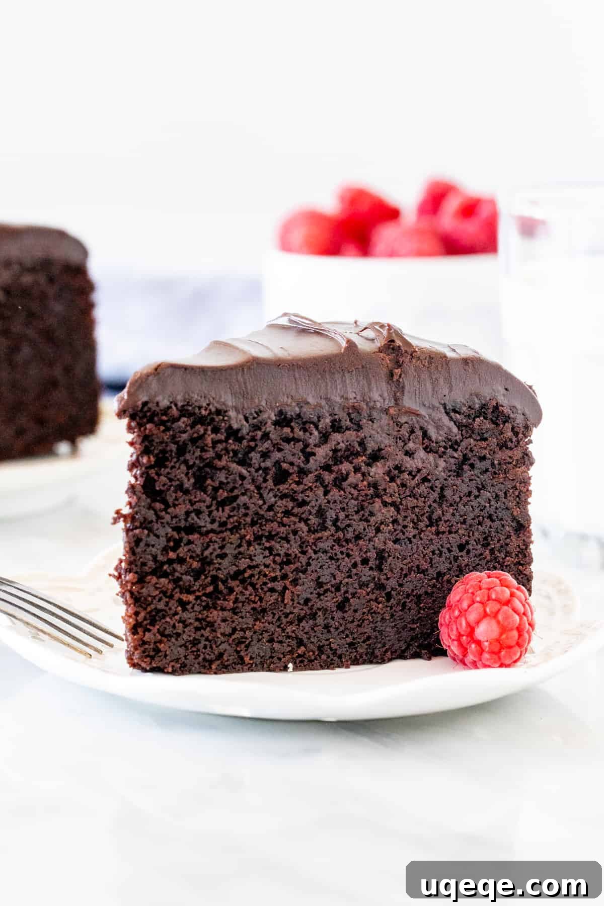 Decadent Chocolate Mud Cake 2 A perfectly sliced piece of chocolate mud cake revealing its moist, fudgy interior, topped with a thick layer of glistening chocolate ganache.
