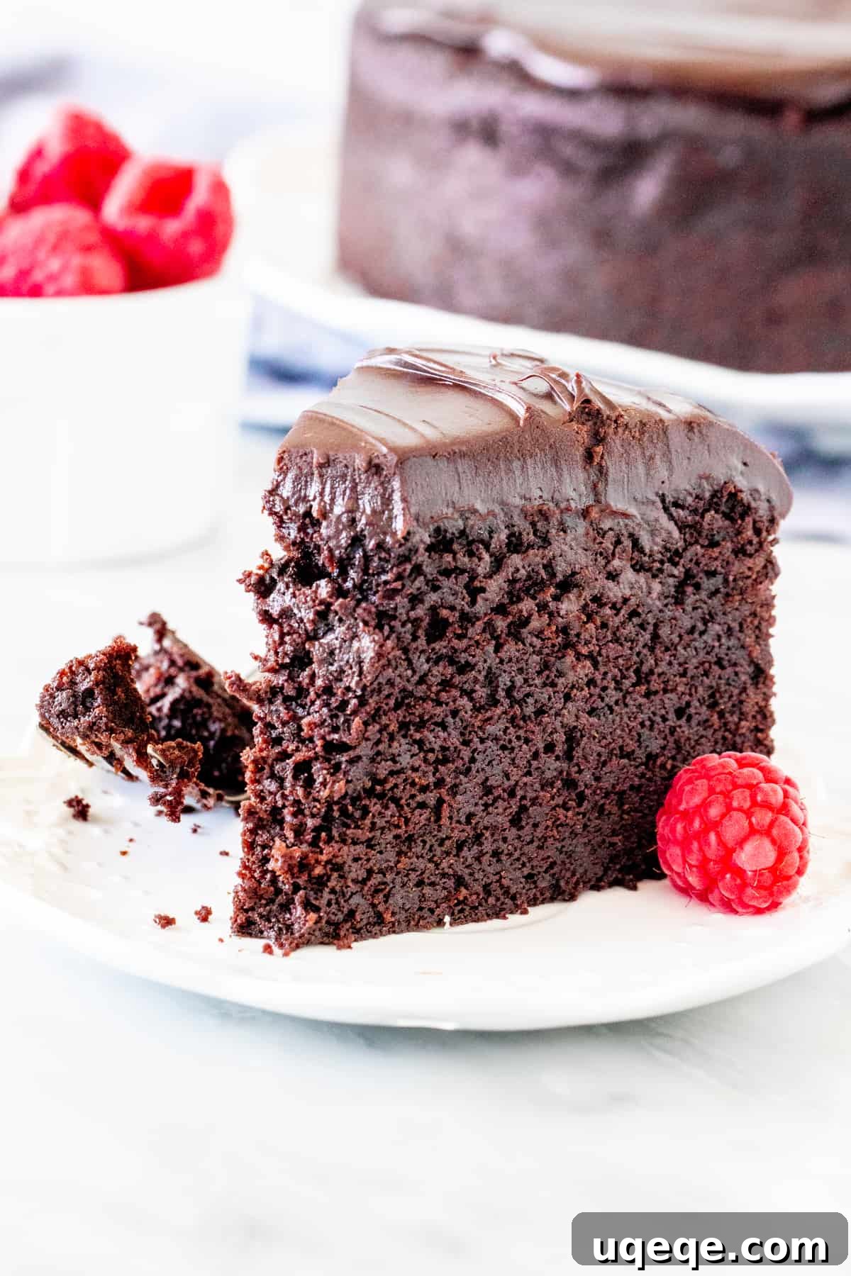 Decadent Chocolate Mud Cake 6 A close-up of a slice of fudgy chocolate mud cake with a bite taken out, showing its deep color and moist texture, topped with ganache.