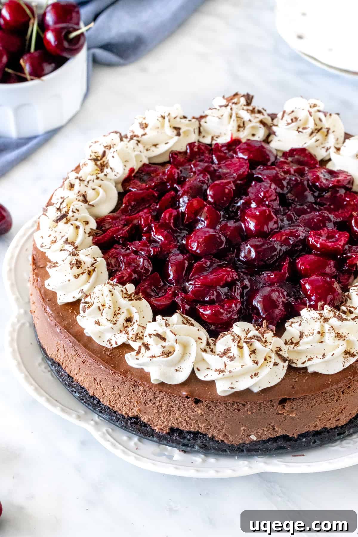 A whole Black Forest Cheesecake on a serving plate, beautifully garnished
