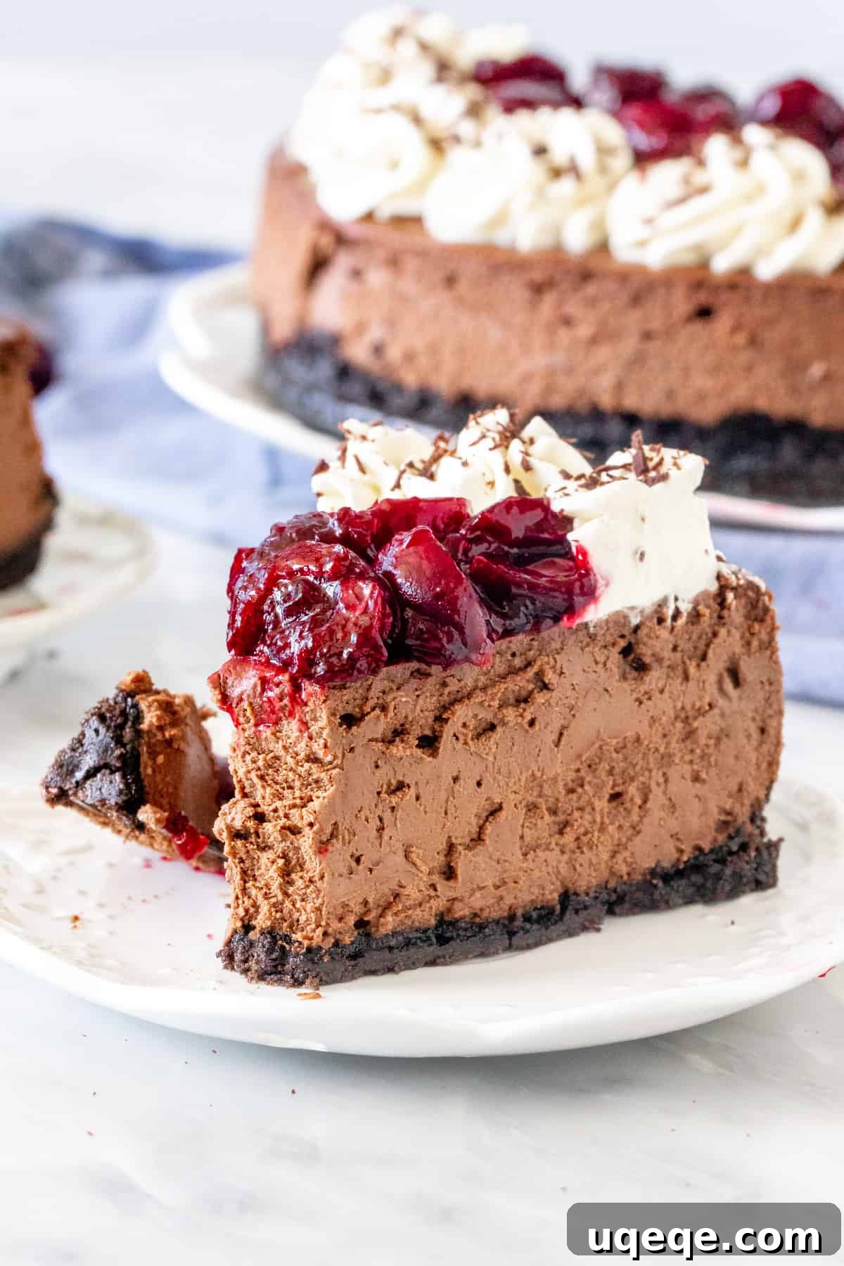 A close-up of a slice of chocolate cheesecake with vibrant cherry sauce on top