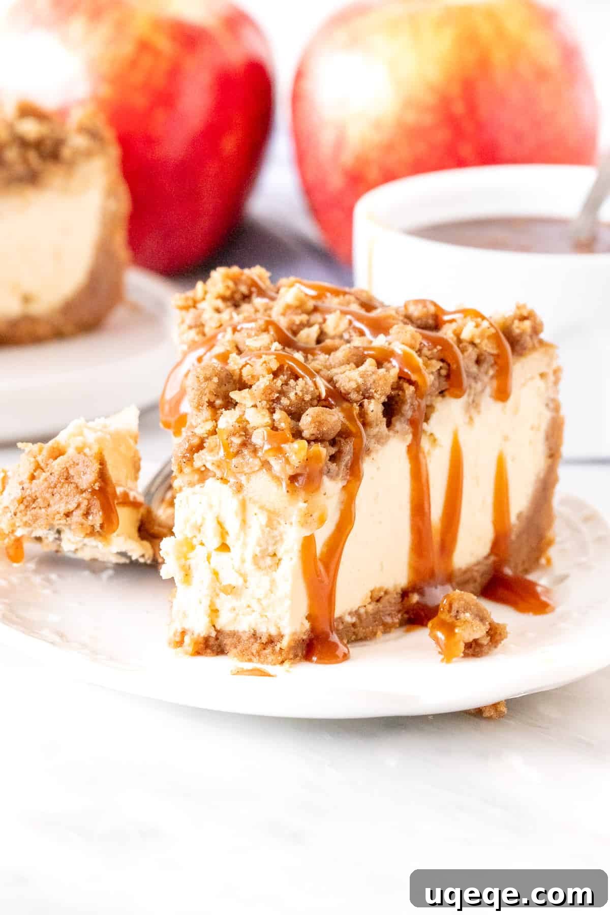A mouth-watering close-up of a slice of Apple Crisp Cheesecake, revealing its distinct layers of golden oatmeal crumble, tender spiced apples, creamy vanilla cheesecake, and crunchy graham cracker crust. A bite has been taken, showing the delightful cross-section, with a hint of caramel drizzle.