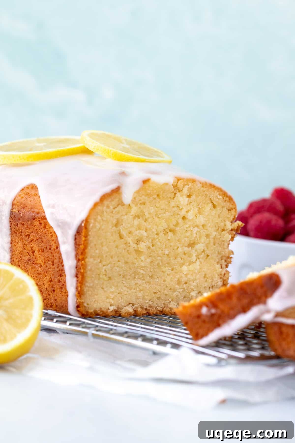 Zesty Lemon Loaf: Ultra Moist and Glazed to Perfection 2 Lemon loaf with lemon glaze, on a cooling rack with slices cut, showcasing its moist texture and golden crust