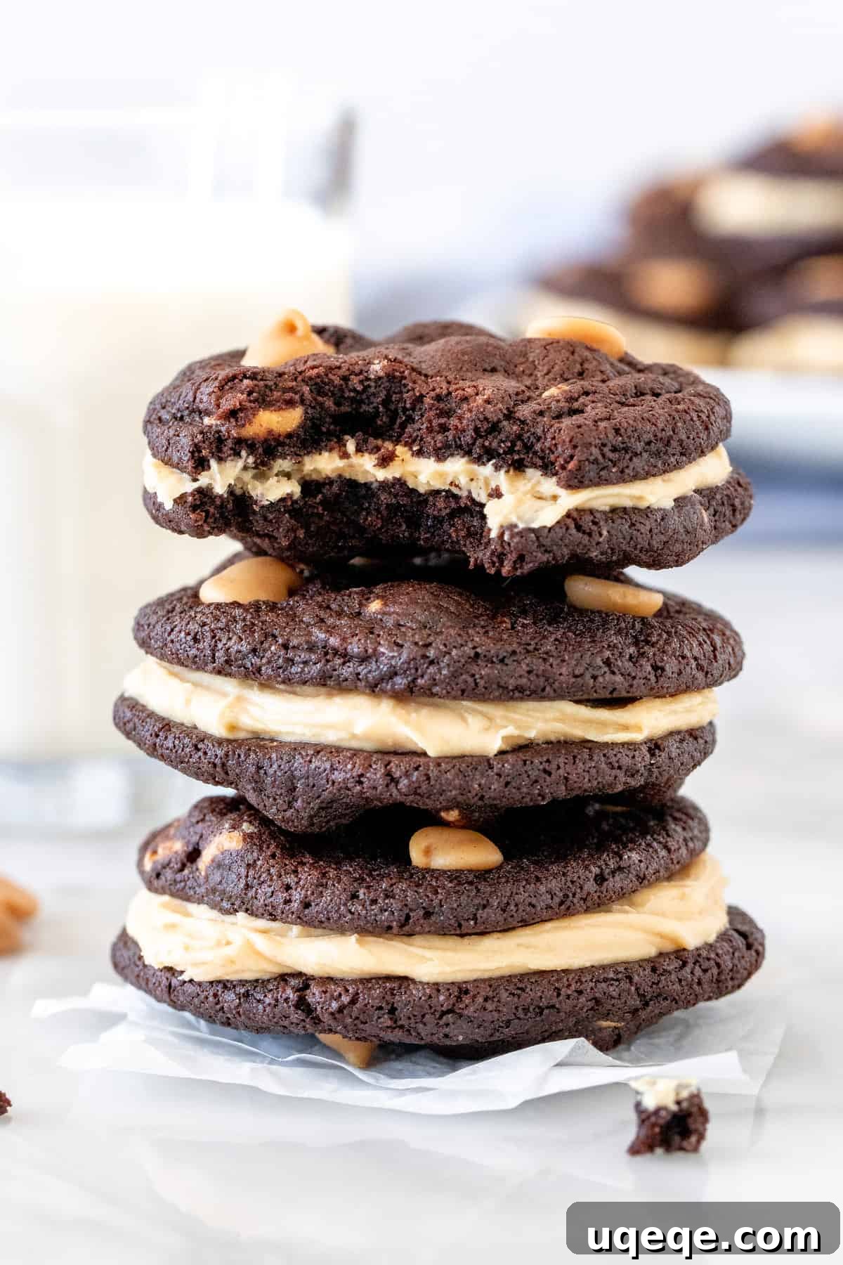 Decadent Chocolate Peanut Butter Stacks 4 Stack of three chocolate peanut butter sandwich cookies next to a glass of milk, emphasizing their rich and indulgent nature