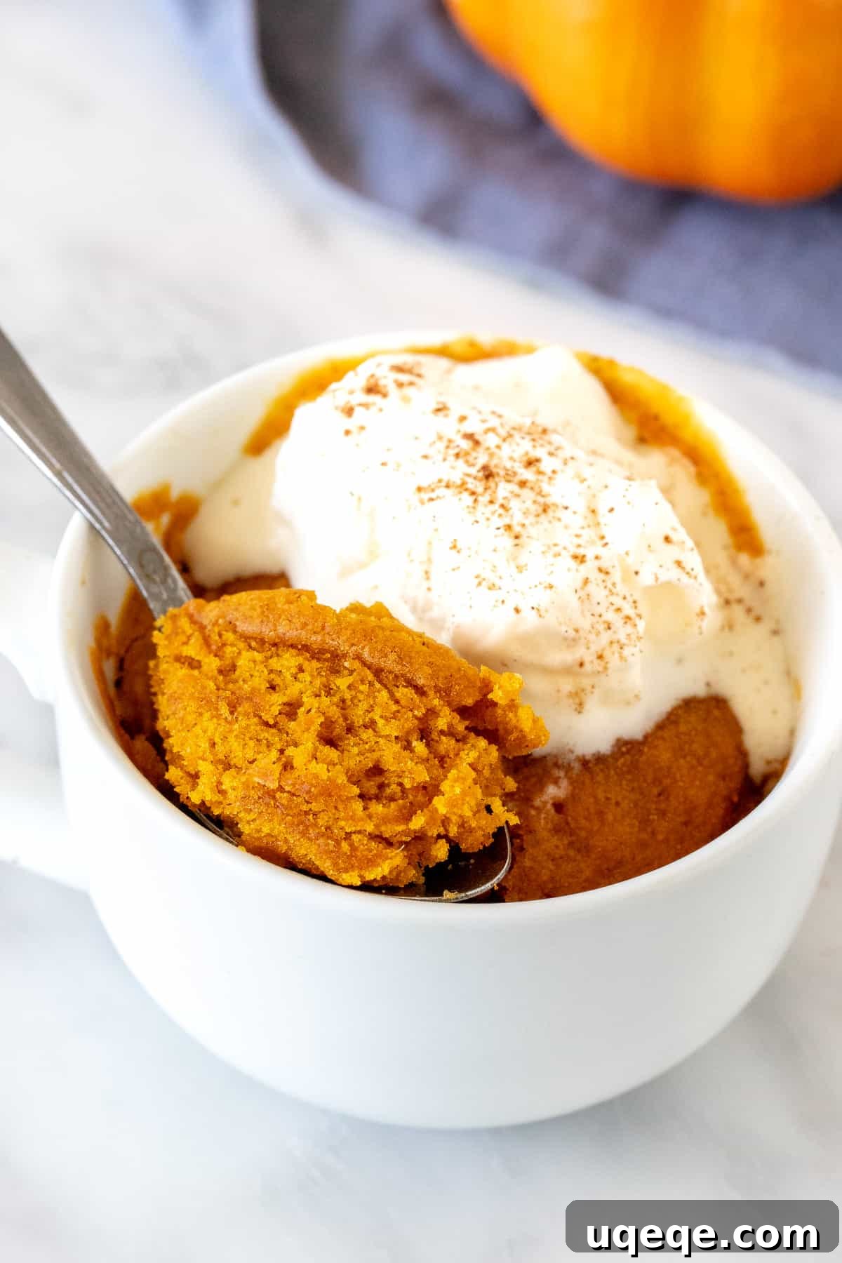 Spiced Pumpkin Mug Delight 2 Moist and flavorful pumpkin mug cake topped with a dollop of whipped cream, ready for a cozy fall treat
