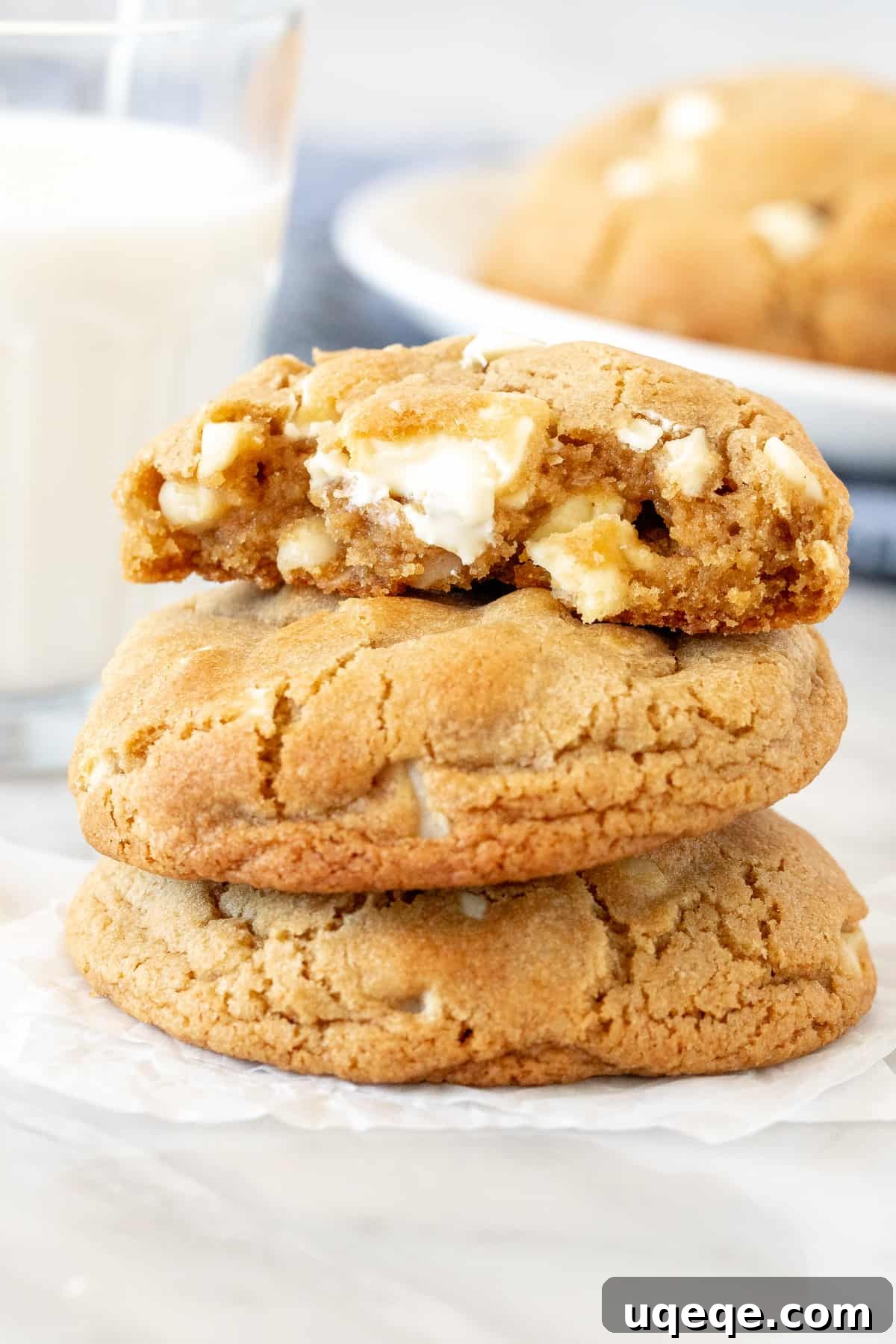 Gourmet White Chocolate Macadamia Cookies 2 Stack of bakery-style white chocolate macadamia cookies with top cookie broken in half.