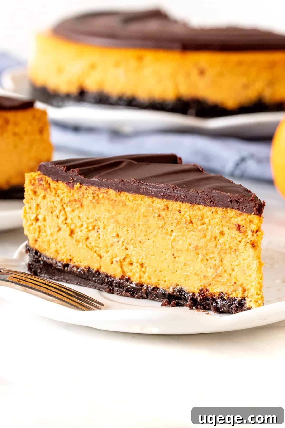 Slice of creamy pumpkin chocolate cheesecake with a generous layer of chocolate ganache