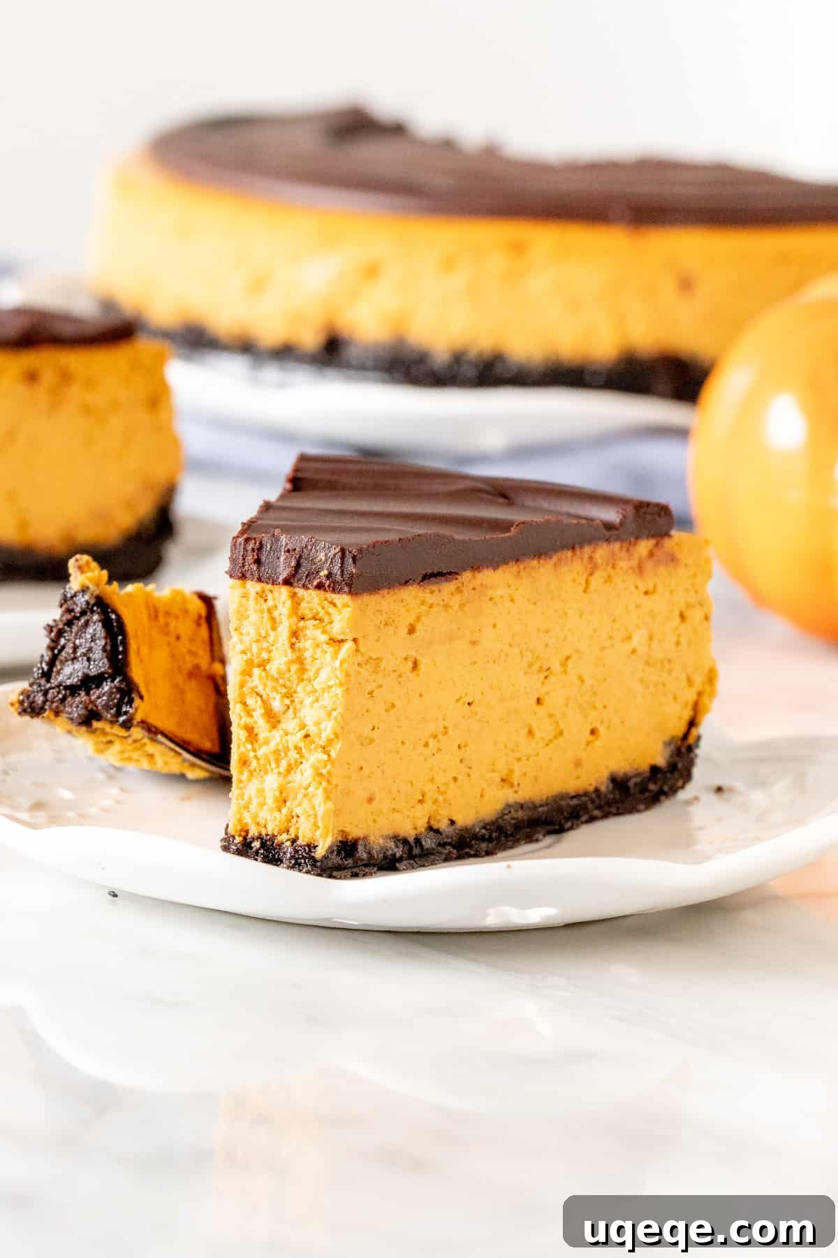 Piece of pumpkin chocolate cheesecake with a crisp Oreo crust and a bite taken out, revealing its creamy texture
