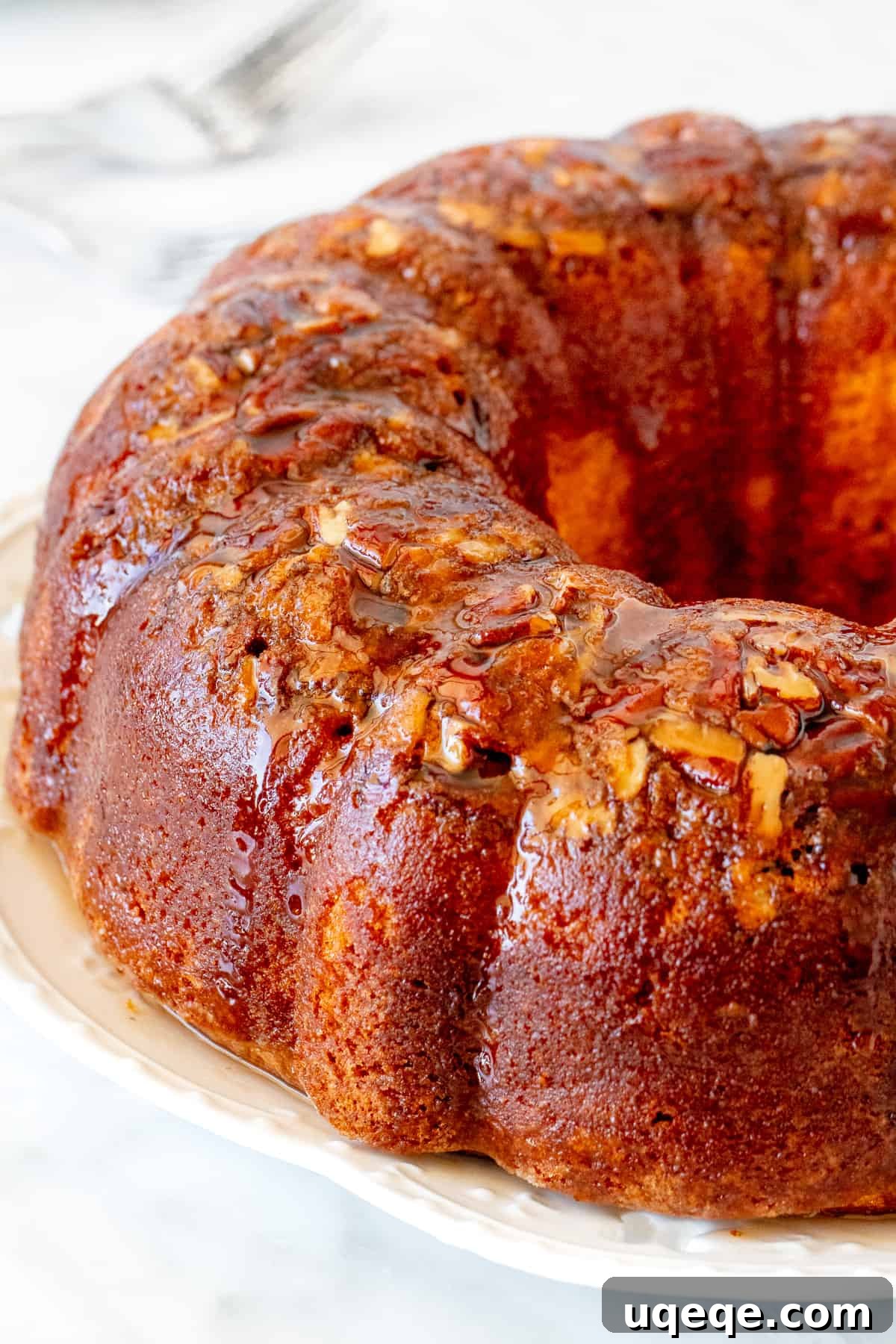 Decadent Homemade Rum Cake 2 Rum-soaked bundt cake with pecans, glistening with rum butter sauce, ready to be sliced.