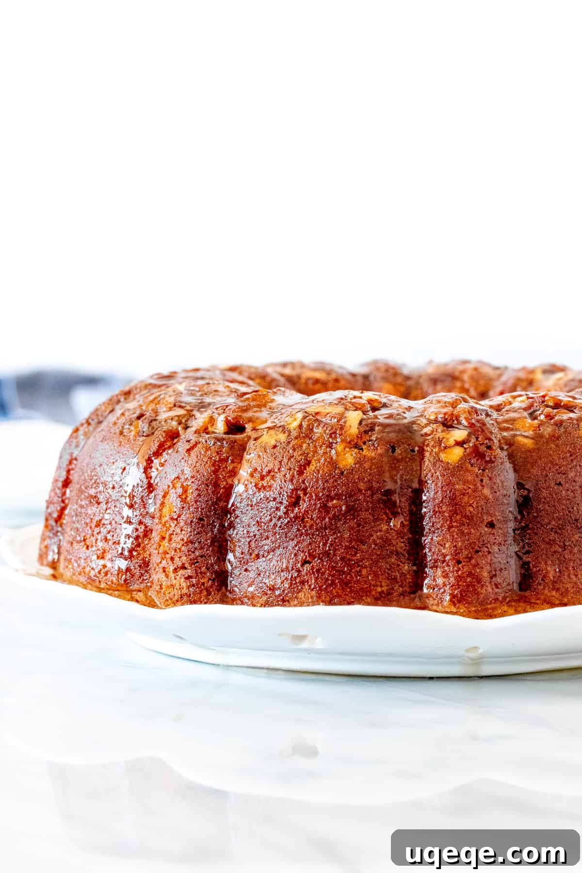 Decadent Homemade Rum Cake 3 Close-up of a golden brown bundt cake with butter rum sauce poured over it.