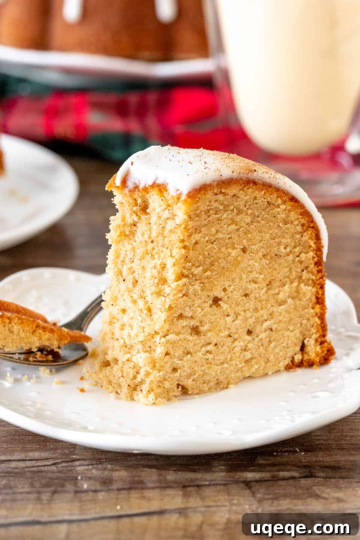 Holiday Eggnog Bundt Cake: Incredibly Moist, Tender, and Festive 5 Slice of eggnog pound cake with a bite taken out of it and a glass of eggnog for a festive Christmas treat
