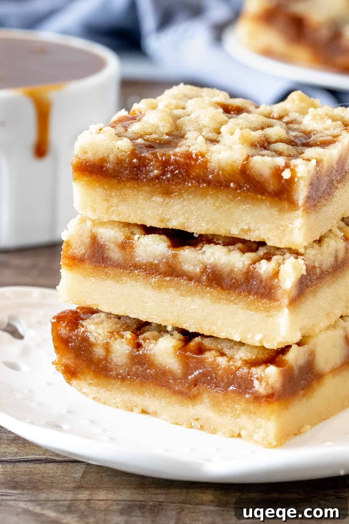Salted Caramel Shortbread Crumble Bars 2 Stack of three golden-brown caramel crumb bars showcasing their distinct layers of shortbread, caramel, and crumb topping.
