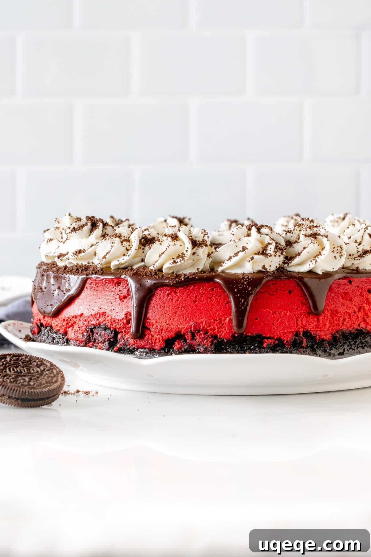 Velvety Oreo Dream Cheesecake 3 A top-down view of a full 9-inch round Red Velvet Oreo Cheesecake, showcasing its flawless surface, rich red color, a perfectly baked Oreo crust, and elegant decorations of chocolate ganache, piped whipped cream rosettes, and sprinkled crushed Oreos.