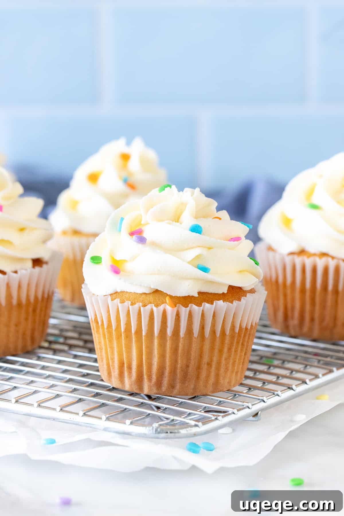 Effortless White Frosting Secrets 6 Cupcakes on a wire rack with bright white frosting