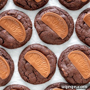 A close-up of a chocolate orange cookie with a melted chocolate orange segment, on a white plate.