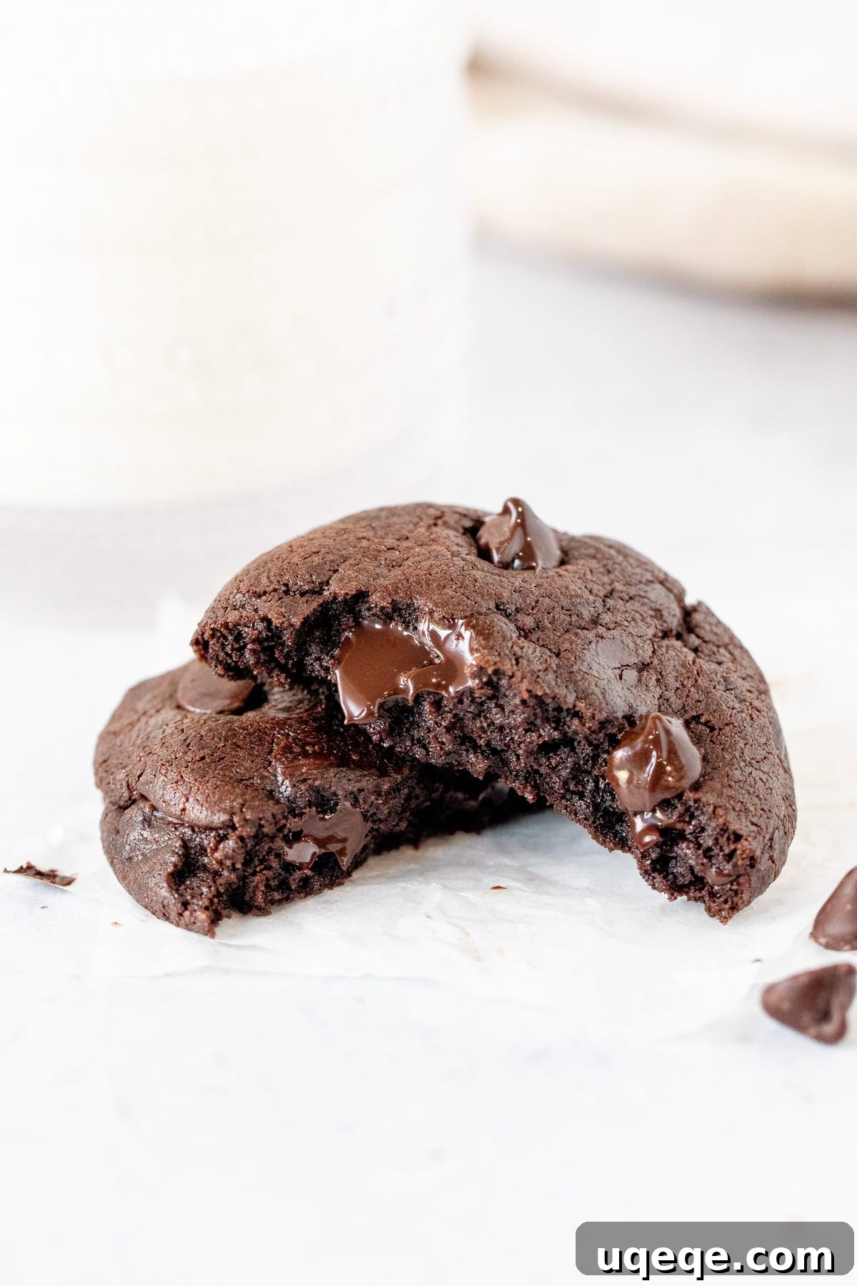 Decadent Double Chocolate Cookies 8 A thick double chocolate chip cookie, perfectly broken in half to reveal its soft, chocolatey interior, served next to a refreshing glass of milk.