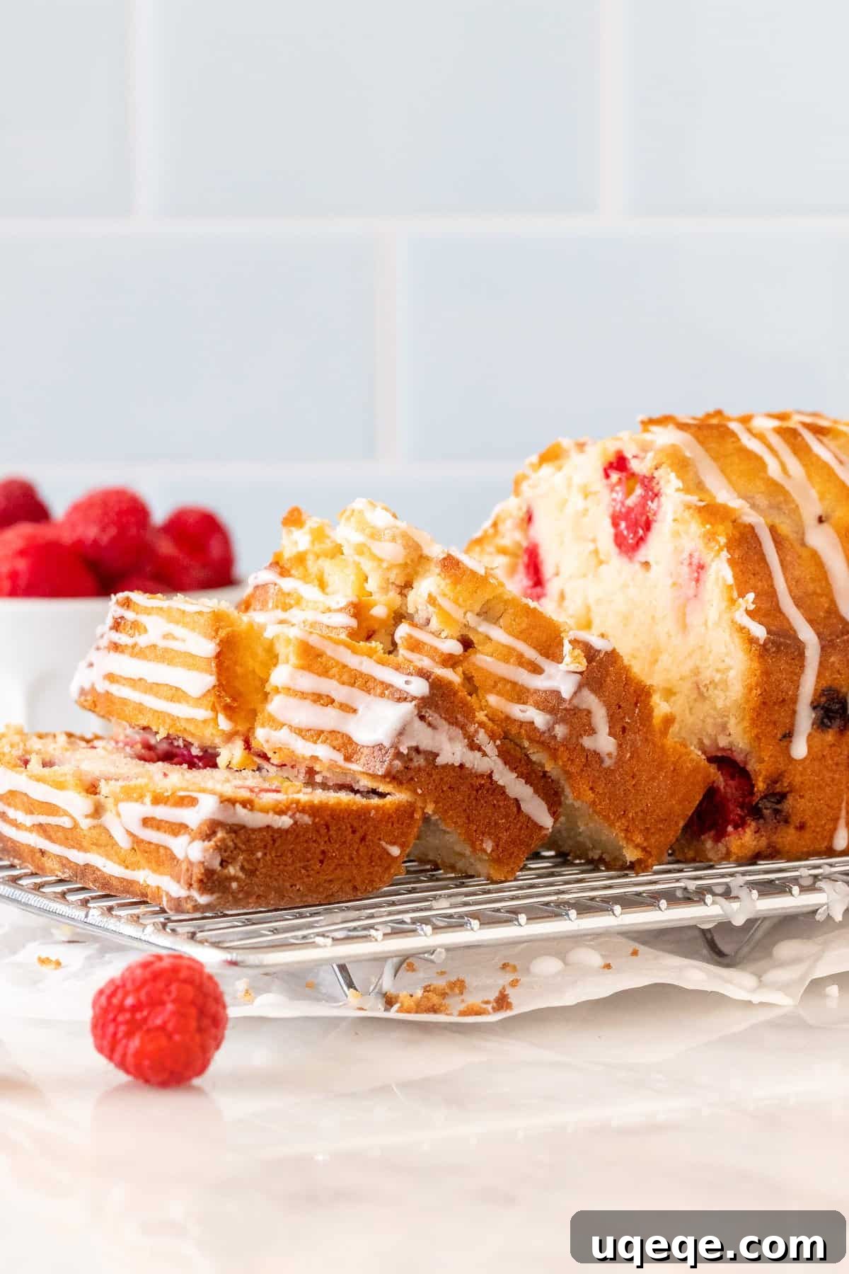 Tender Raspberry Bread Bursting with Juicy Berries 2 Moist Raspberry bread with 3 slices cut on a cooling rack, showcasing its tender crumb and berry distribution