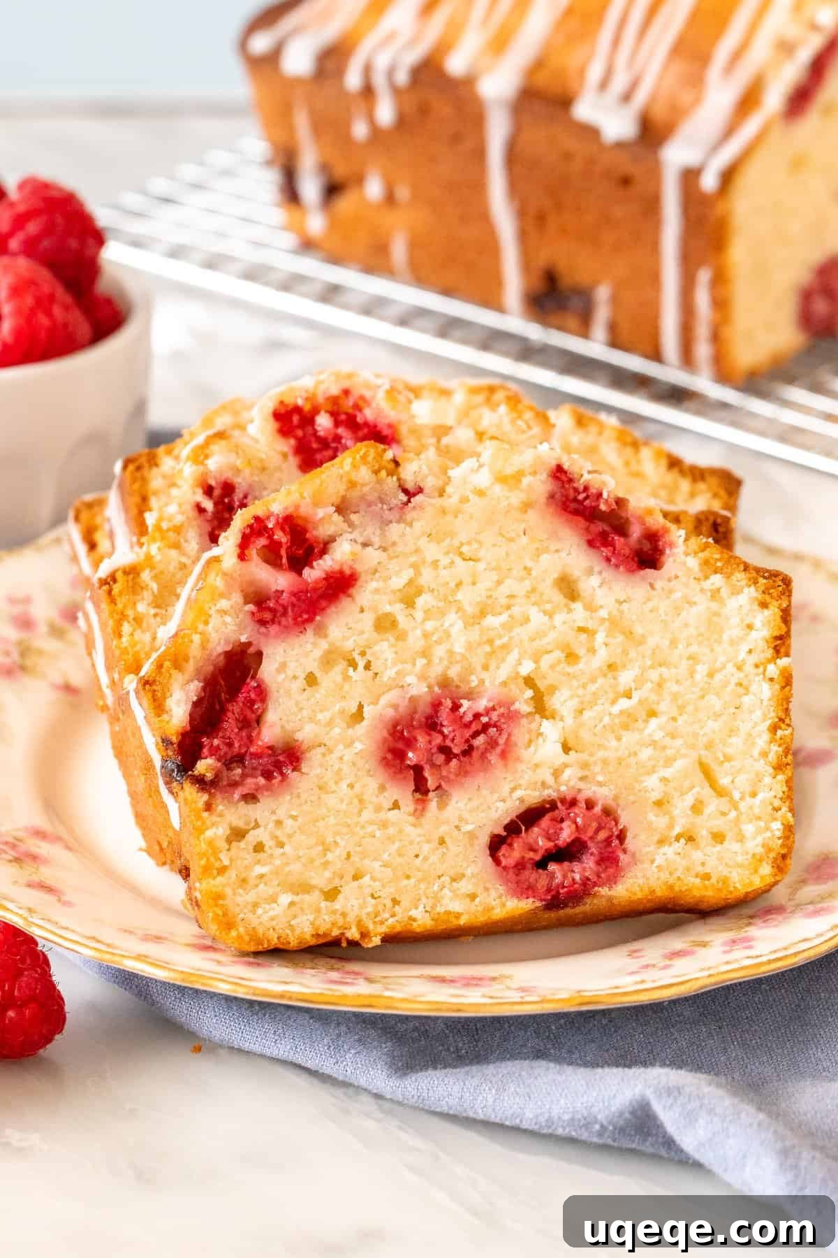 Tender Raspberry Bread Bursting with Juicy Berries 4 Close-up of moist raspberry bread slices on a white plate, highlighting the perfectly baked crust and berry distribution