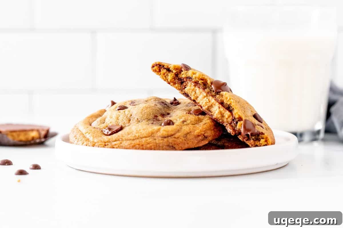 Decadent Reese's Chocolate Chip Cookies 3 Plate of Reese's chocolate chip cookies with one cookie broken in half revealing the peanut butter cup, alongside a glass of milk.