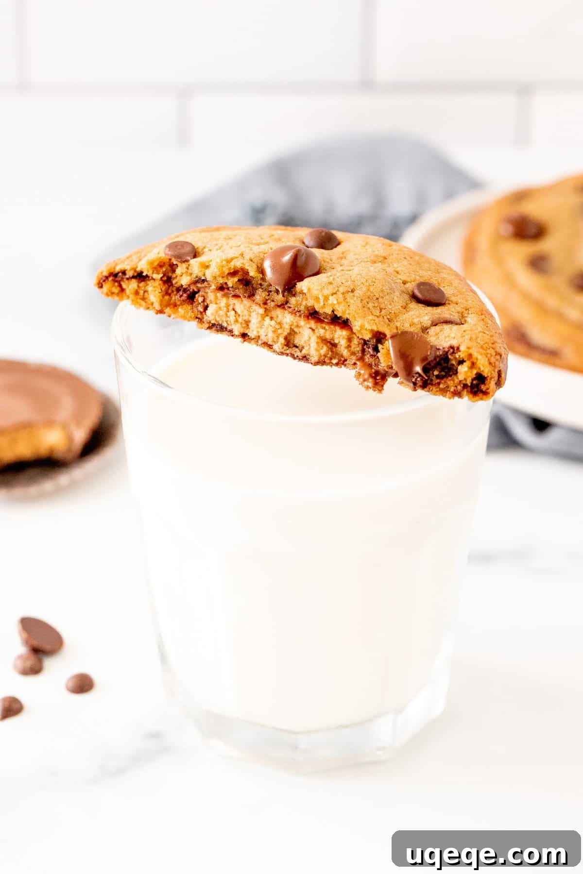 Decadent Reese's Chocolate Chip Cookies 6 Half of a Reese's chocolate chip cookie balanced on top of a glass of milk, showing the gooey peanut butter center.