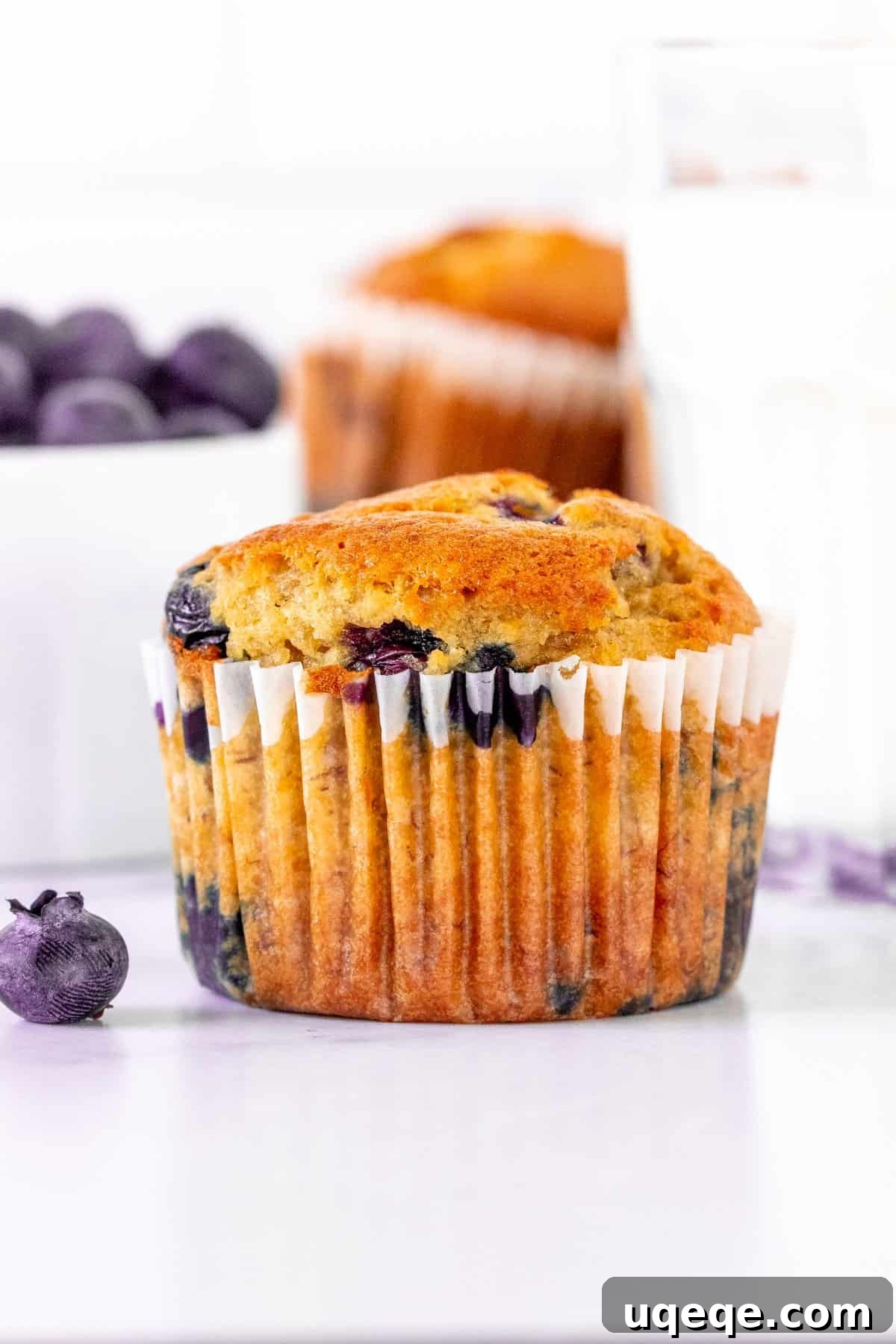 A deliciously moist banana blueberry muffin with a glass of milk, highlighting its soft, crumbly texture and abundant, juicy blueberries throughout.