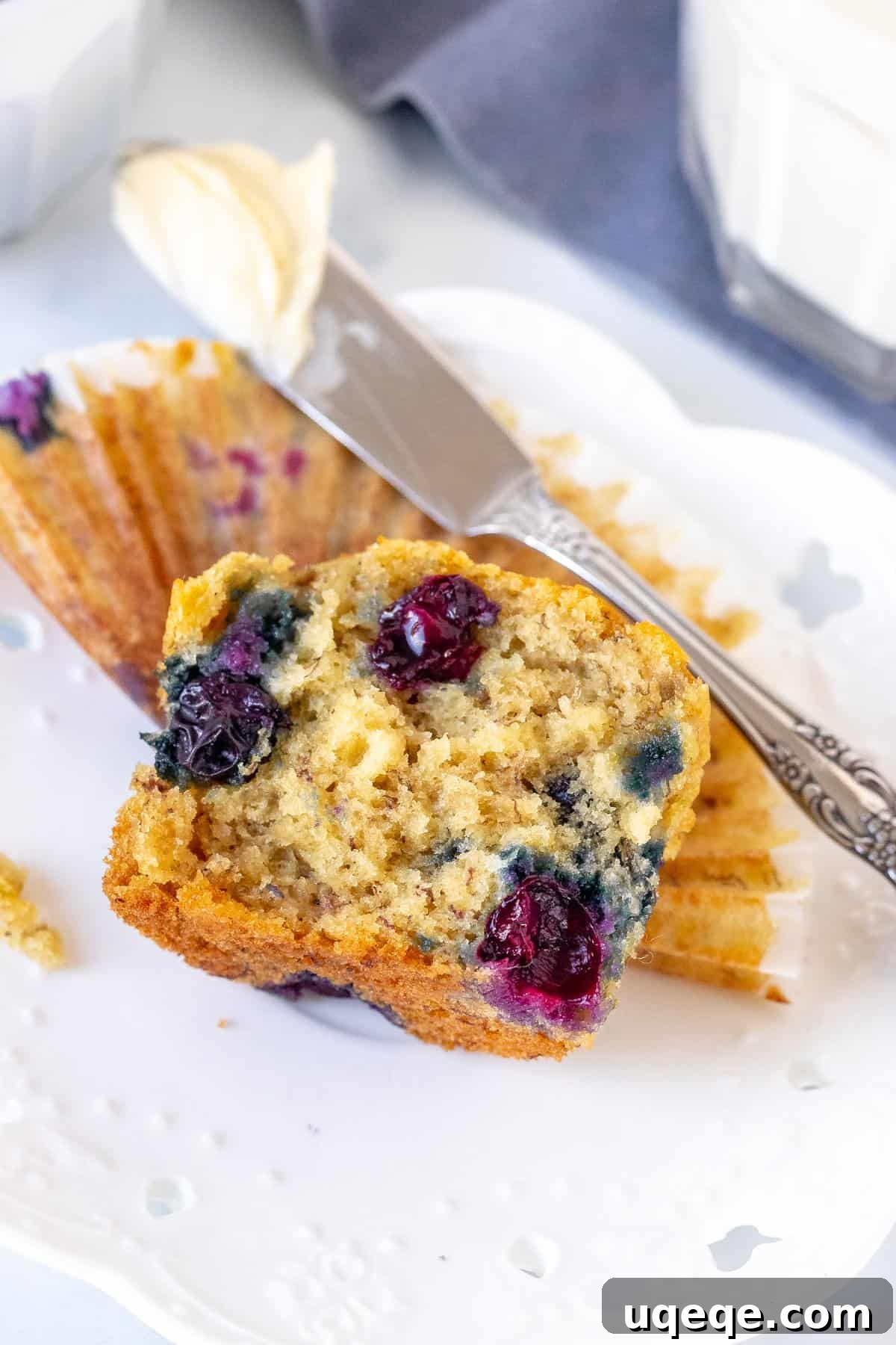 A freshly baked banana blueberry muffin expertly broken in half, proudly revealing its wonderfully moist interior and the delightful scattering of sweet blueberries throughout its tender crumb.
