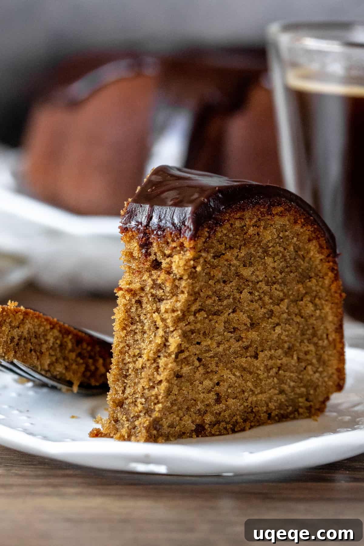 Velvet Coffee Bundt 8 A close-up shot of a slice of coffee bundt cake with a bite taken out, highlighting its moist texture and rich chocolate ganache topping.
