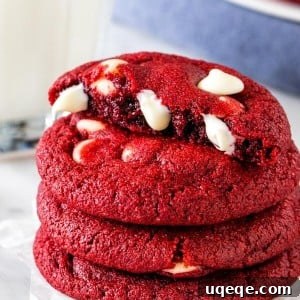 Ruby Red Chocolate Chip Indulgence 6 A stack of red velvet chocolate chip cookies, with the top cookie broken in half.