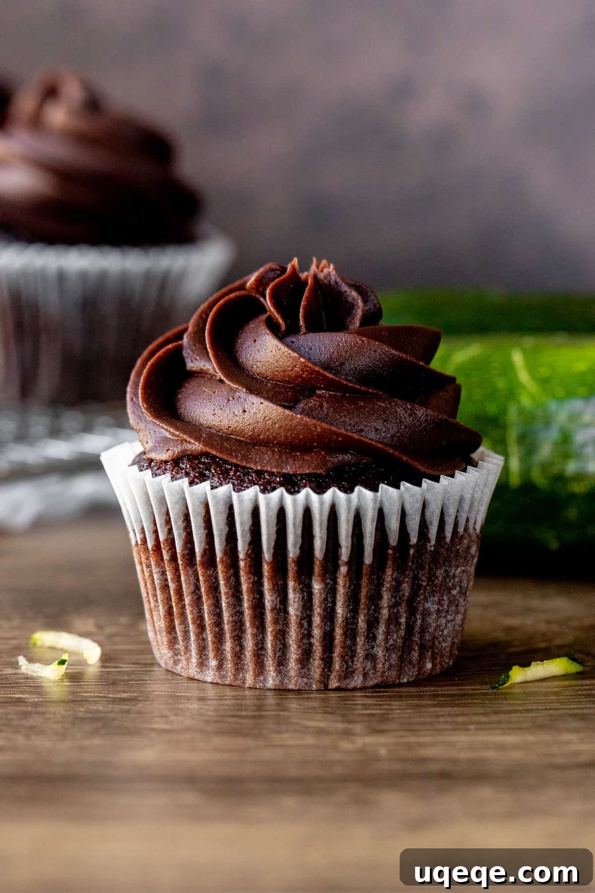 Decadent Chocolate Zucchini Cupcakes 2 Chocolate zucchini cupcake with zucchini and cupcakes in background