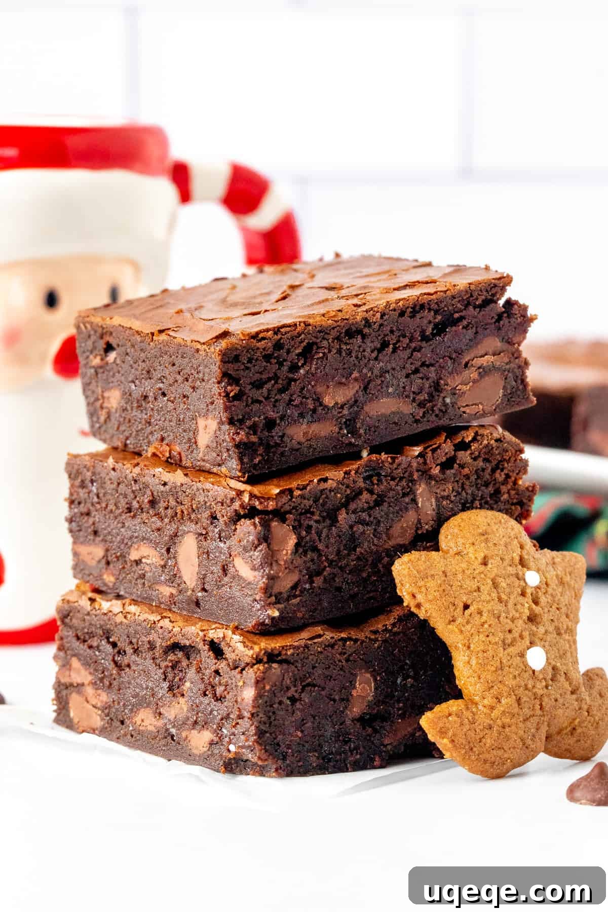 A beautiful close-up of three gingerbread brownies stacked on top of each other, showcasing their fudgy texture and delightful crinkled tops.