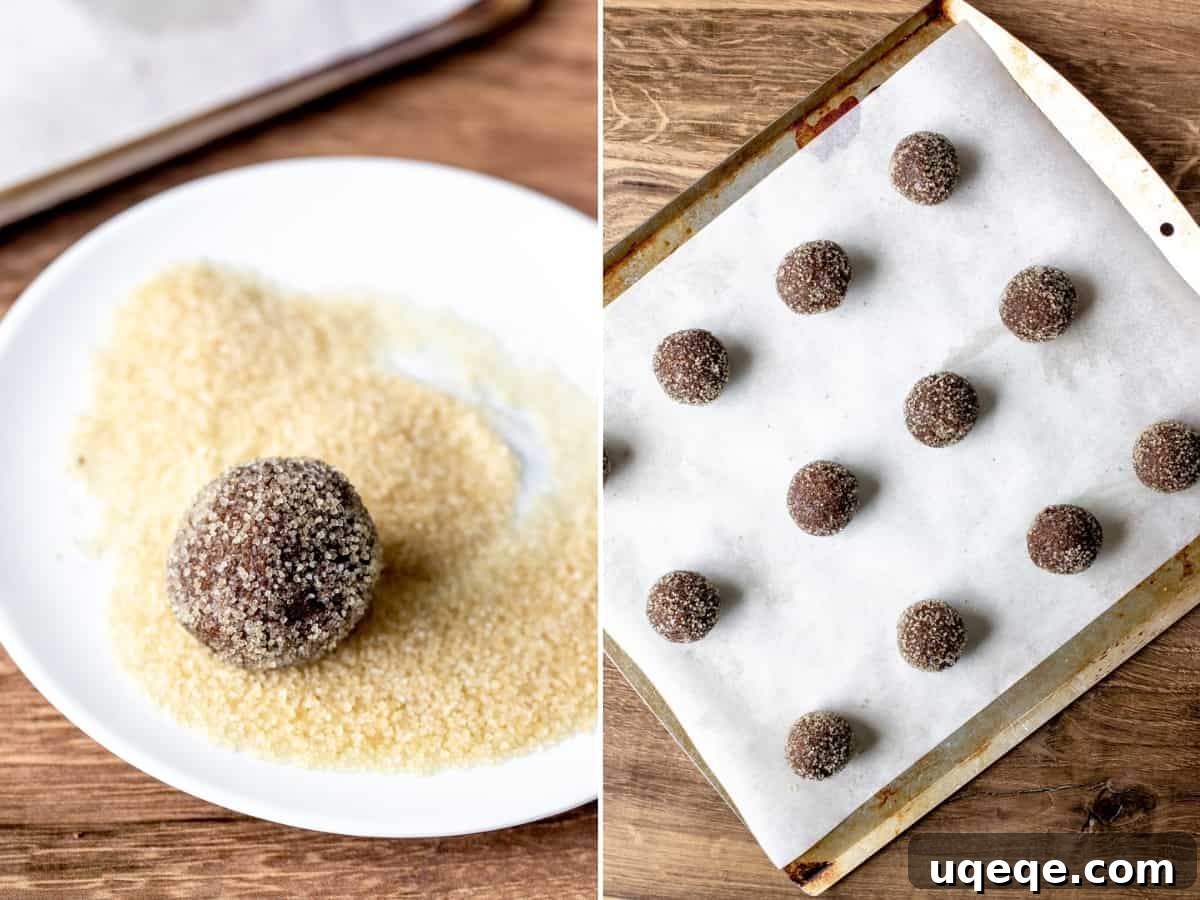 Cookie dough balls rolled in coarse sugar, ready for baking on a parchment-lined cookie sheet. Another dough ball sits on a plate, showcasing the sugary coating.