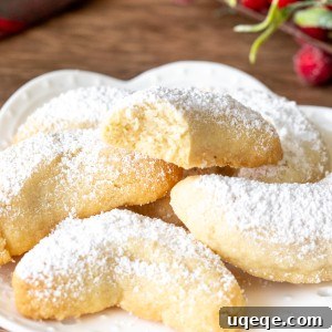 Plate of almond crescent cookies, with one cookie broken in half