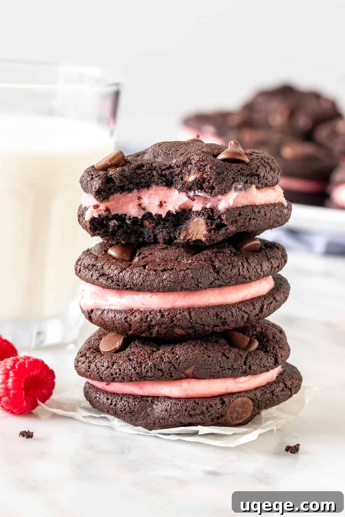 Decadent Chocolate Raspberry Sandwich Cookies 4 A charming stack of three chocolate raspberry sandwich cookies, beautifully showcasing the vibrant pink frosting nestled between the dark chocolate cookies.