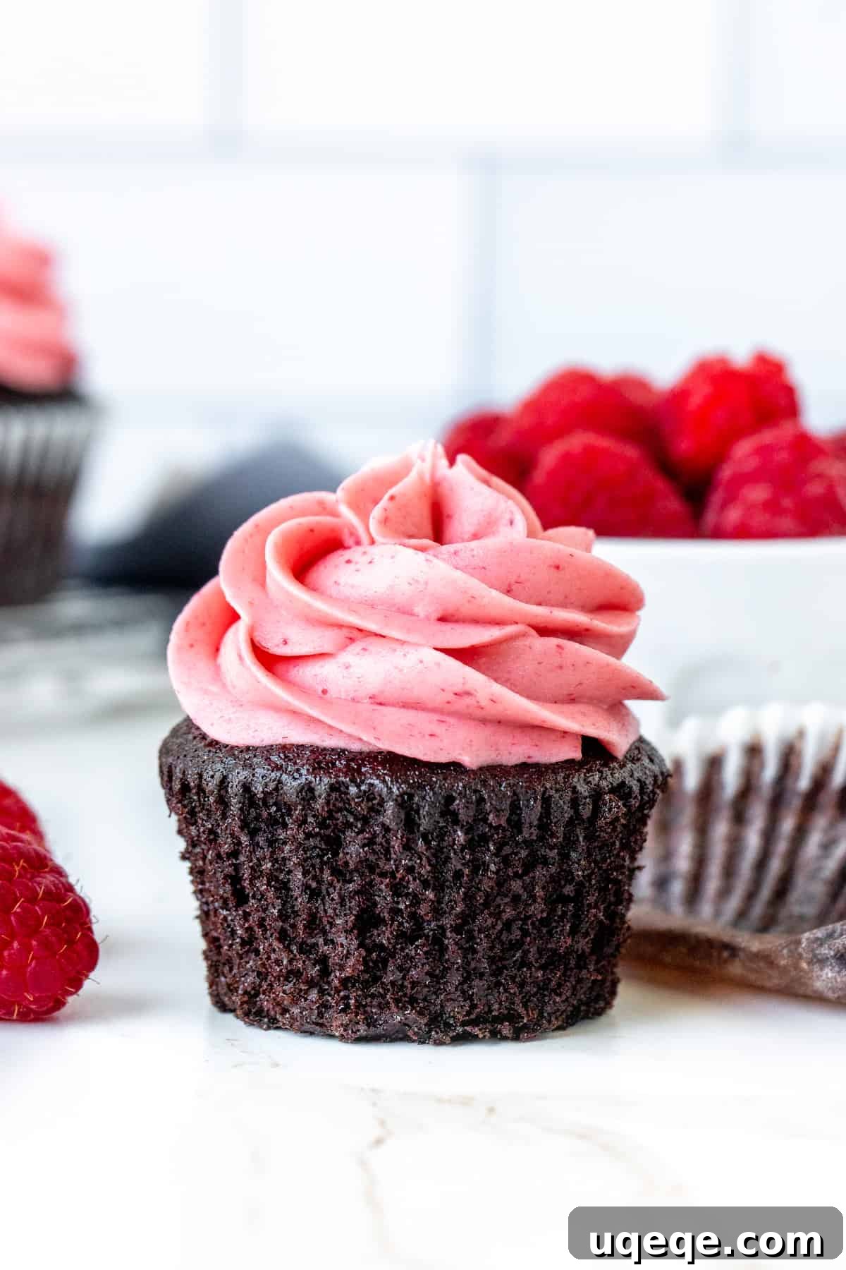 Decadent Chocolate Raspberry Cupcakes 2 Fudgy chocolate cupcake generously frosted with pink raspberry buttercream, muffin paper peeled off.