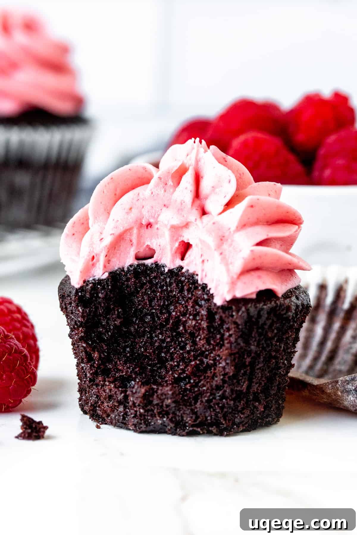 Decadent Chocolate Raspberry Cupcakes 5 A chocolate raspberry cupcake with a bite taken out, revealing the moist chocolate cake and creamy raspberry frosting.