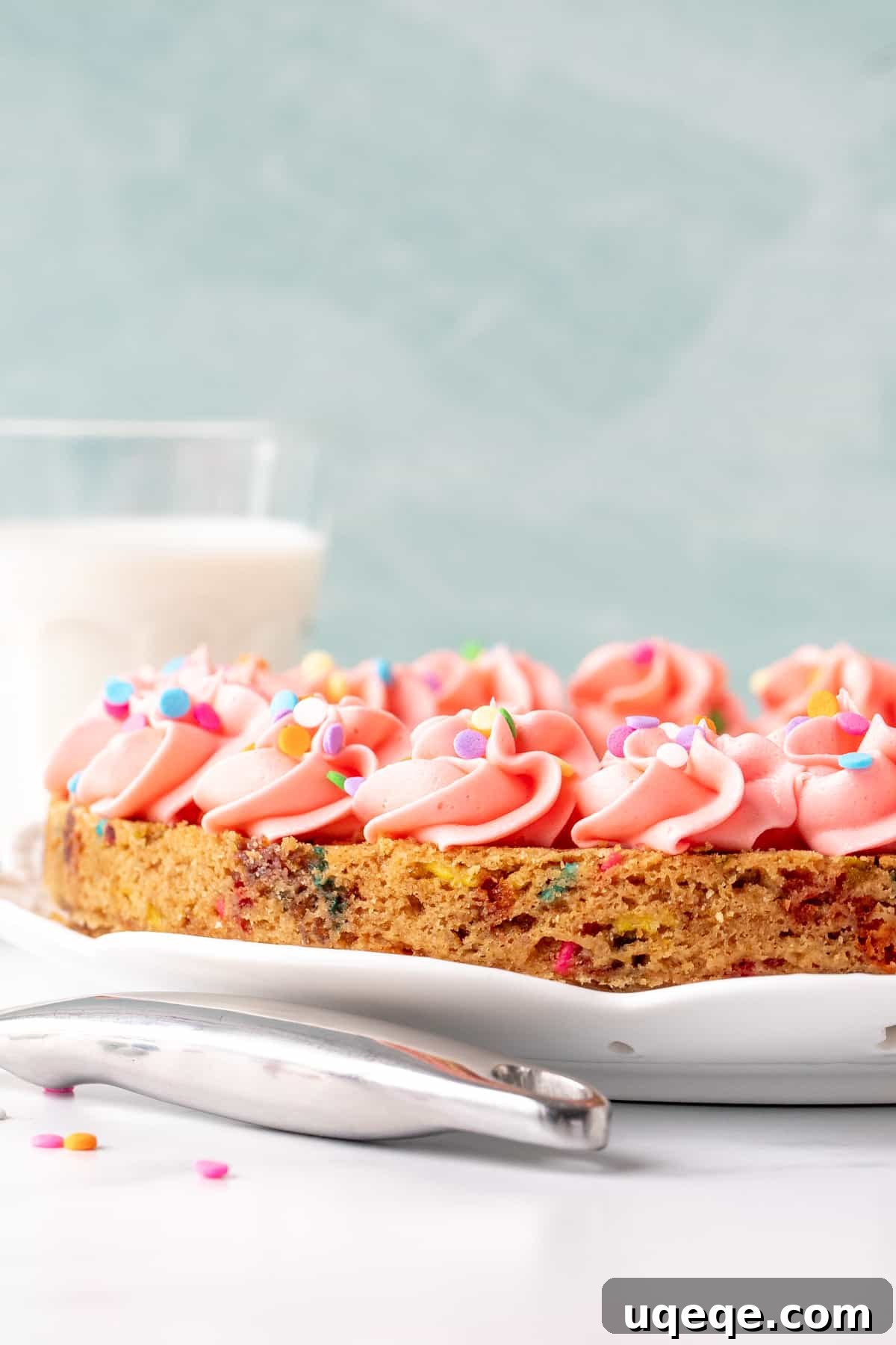 Celebration Sprinkle Cookie Cake 2 A 9-inch round funfetti cookie cake, generously decorated with pink vanilla frosting around the edges and a sprinkle of festive jimmies.