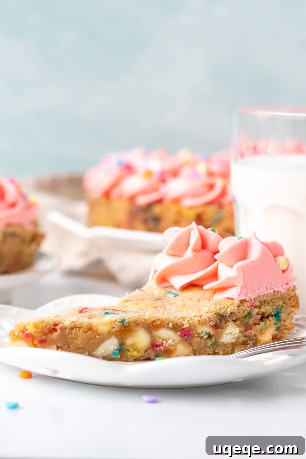 Celebration Sprinkle Cookie Cake 4 A slice of soft and chewy funfetti cookie cake with creamy frosting, served alongside a refreshing glass of milk, highlighting its perfect texture.