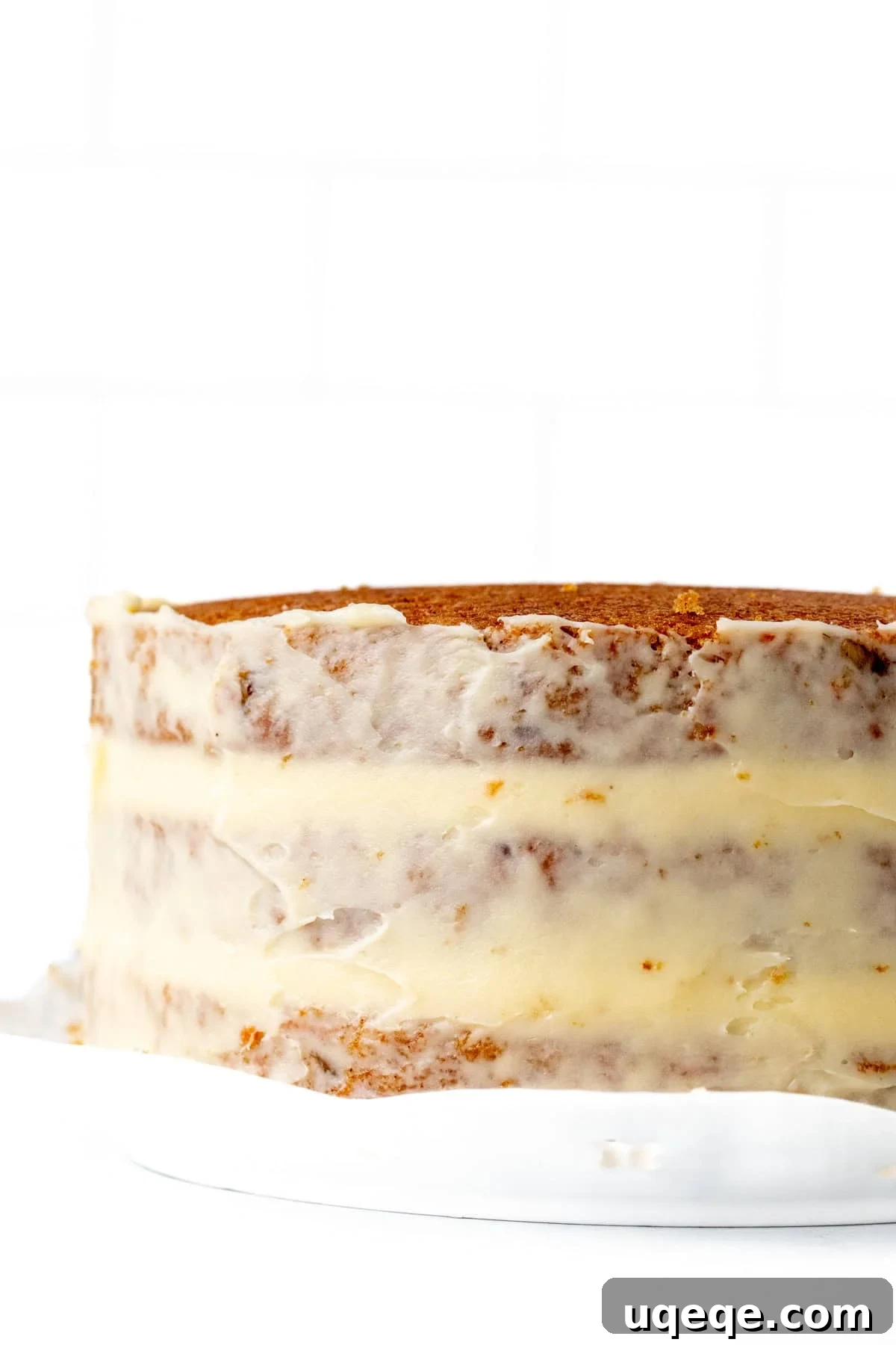 Classic Layered Carrot Cake with Cream Cheese Frosting 7 A three-layer carrot cake with a thin crumb coat of cream cheese frosting, showing the initial stage of assembly.