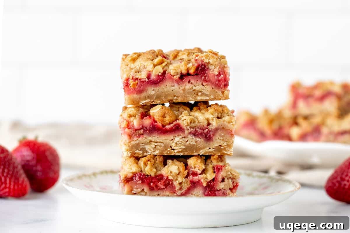 Sweet-Tart Strawberry Rhubarb Squares 6 Stack of 3 homemade strawberry rhubarb oatmeal bars on a wooden surface.