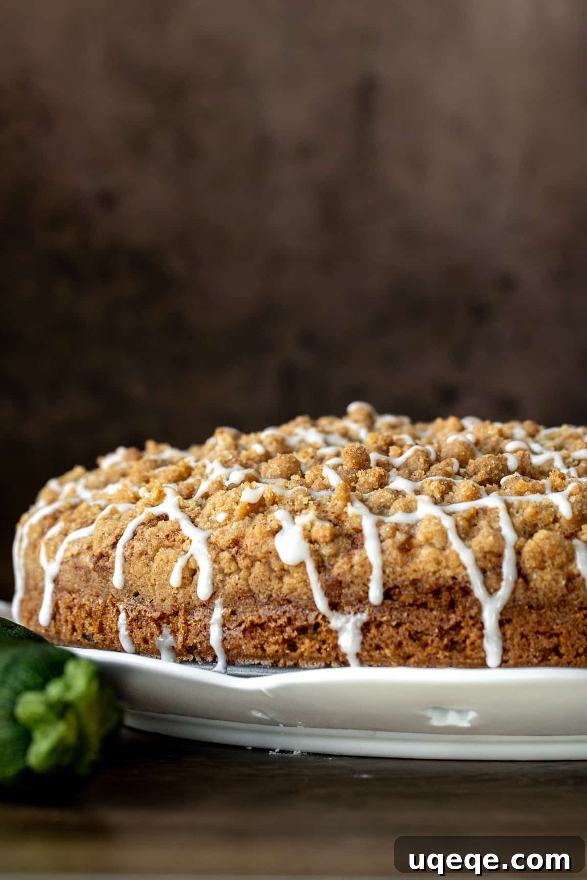 Cinnamon Swirl Zucchini Coffee Cake 8 A beautiful 9-inch round zucchini coffee cake with streusel topping and a delicate glaze drizzle, presented on a white plate.