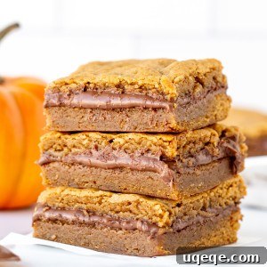Stack of three pumpkin Nutella blondies with a small decorative pumpkin