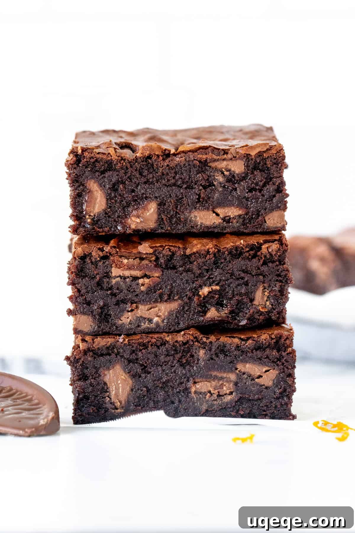 Stack of three chocolate orange brownies, one on top of each other, showcasing their fudgy texture and orange chocolate chunks