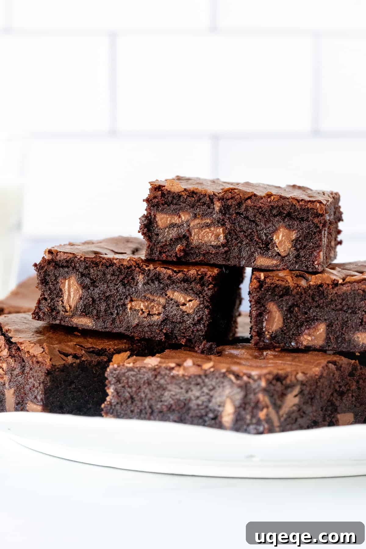 Plate of rich chocolate orange brownies, showing chunks of orange chocolate and their shiny, crinkly tops